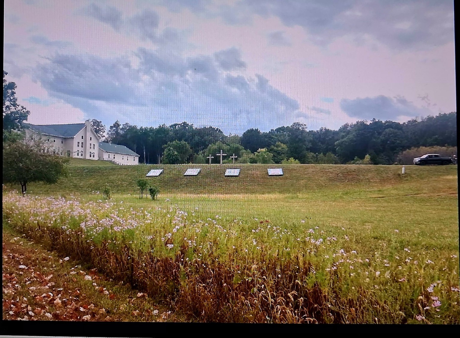 Peaceful NAICFM grounds with a church, flower meadow, and three crosses